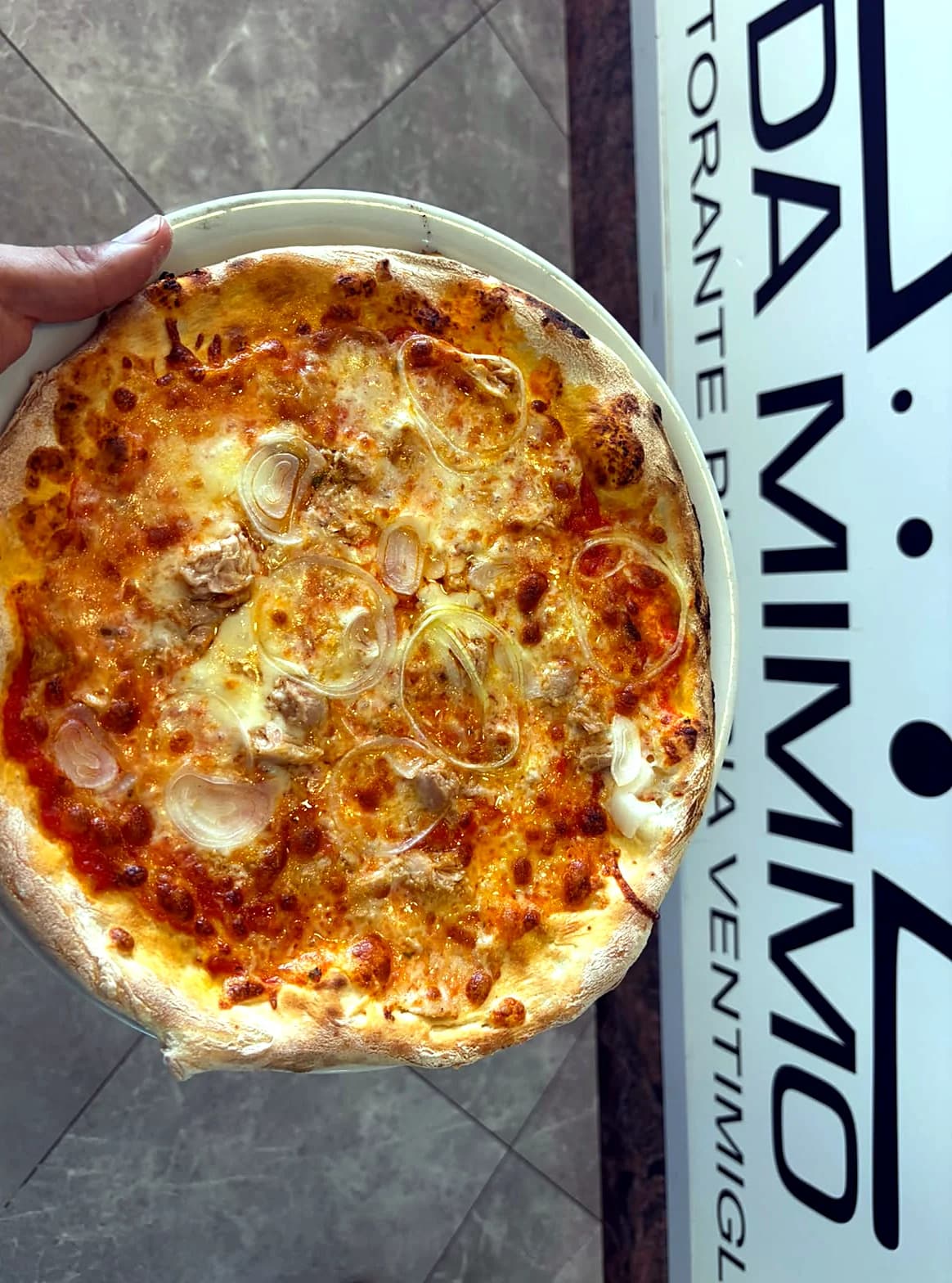 Pizza appena sfornata davanti all'insegna di Da Mimmo